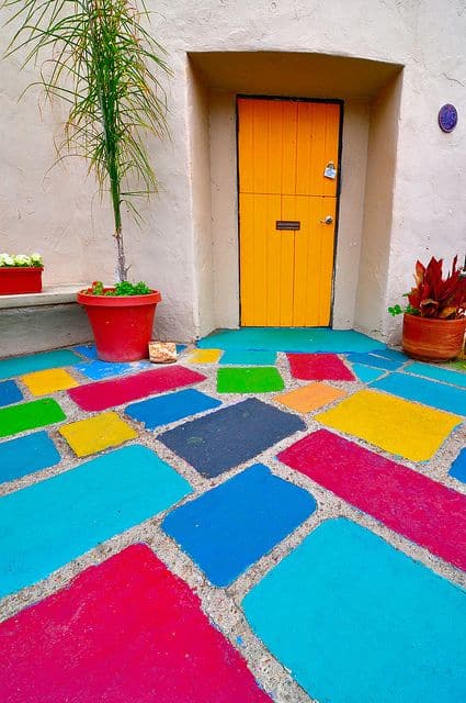 blue, pink, green, yellow floor paints for home entrance and terrace with an orange door