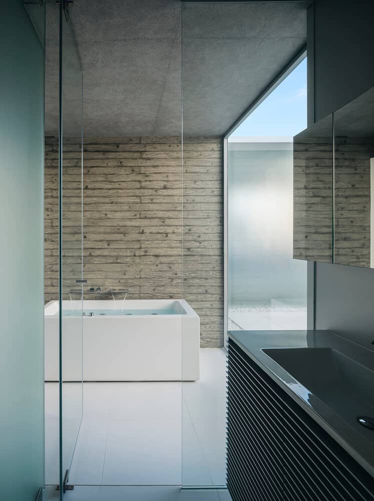 bathroom design with glass door, faux wood wall, and a white bathtub