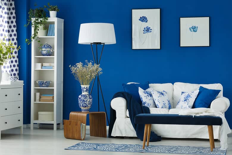  royal blue wall paint colour with white frames and white sofa in front