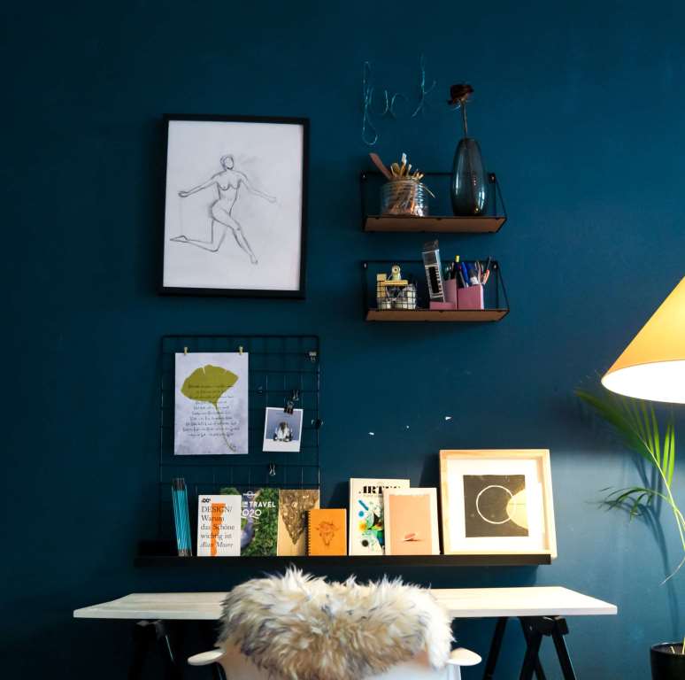  blue coloured wall with books and frames