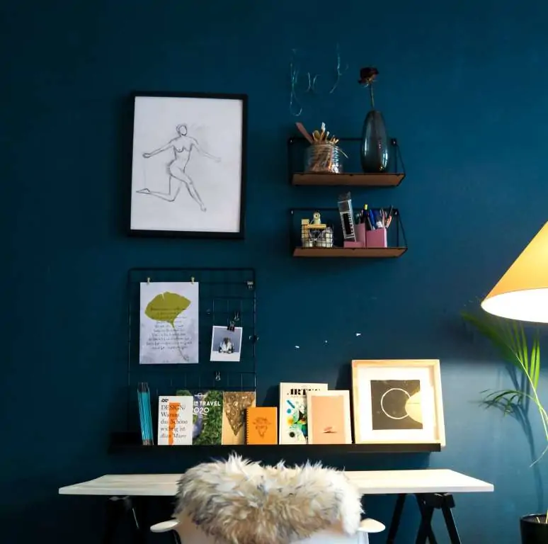  blue coloured wall with books and frames