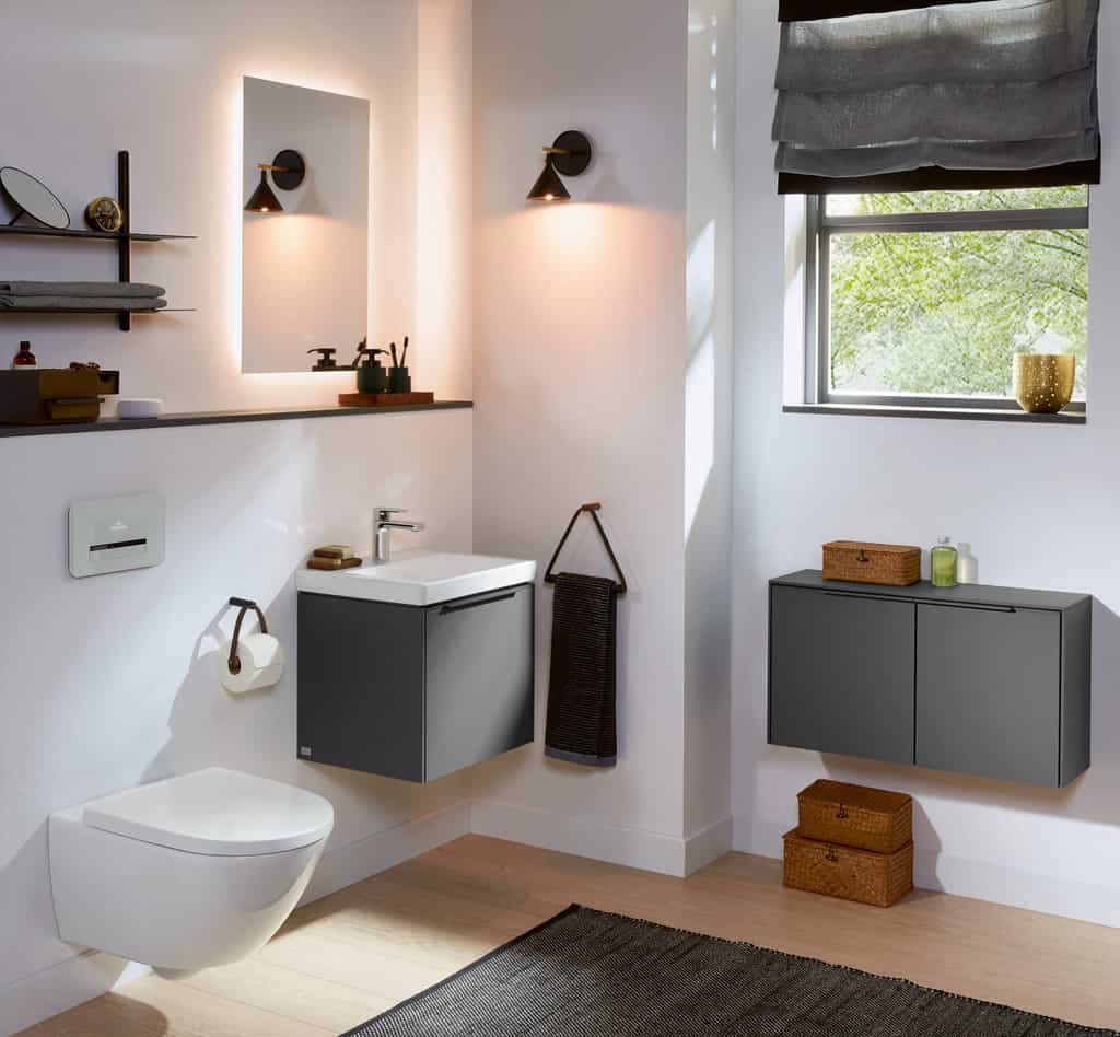 LED bathroom mirror lights in a modern bathroom with grey furniture, hand washbasin and a white wall mounted toilet