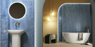 blue bathroom with a washbasin, white bathtub, pendant lights and a stool