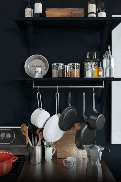 hanging cooking pans, organized spice jars, matte black kitchen walls