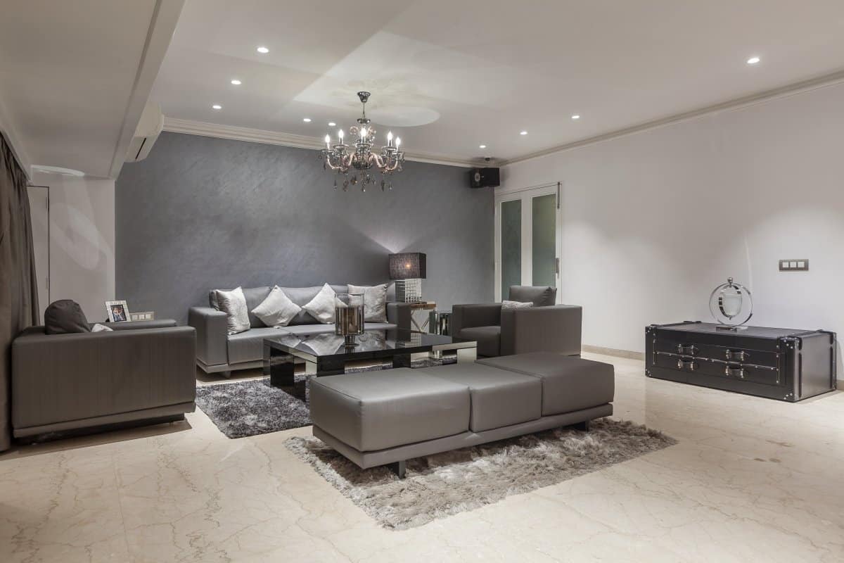 grey living room with sofa and chandelier designed by top interior designers in mumbai in best interior design firms