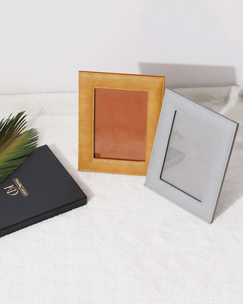 yellow and grey coloured leather frames online for pictures on a white table beside a black book