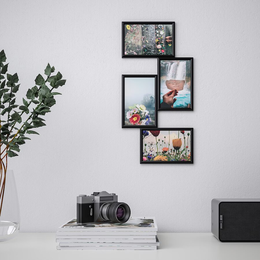 Collage frames on the walls of a drawing room with a home theatre, camera, books, and an indoor plant on a console table