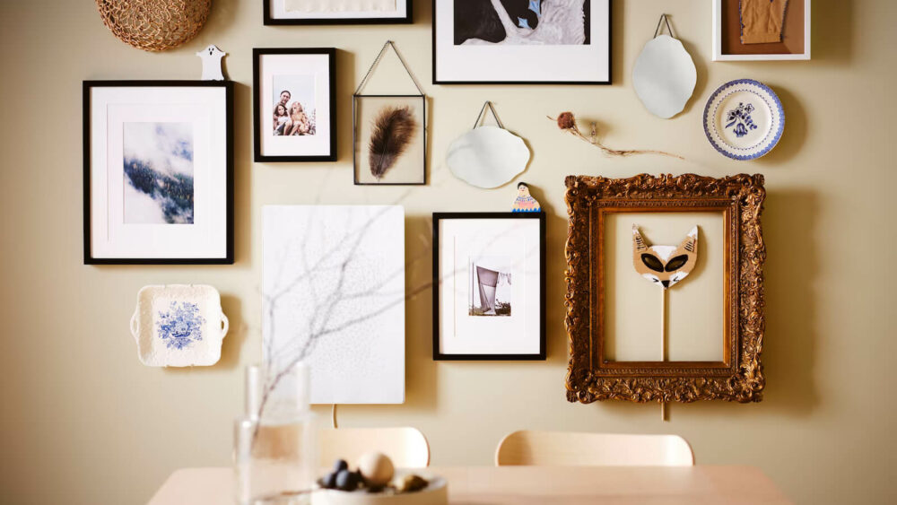 a picture wall over a wooden table with different varieties of photo frames