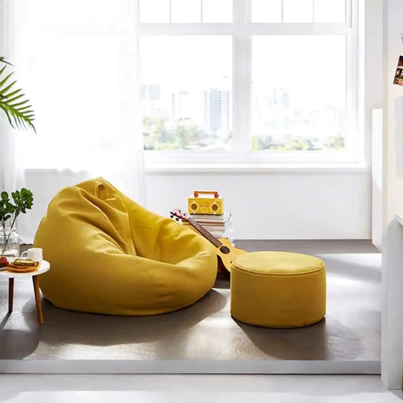 attractive yellow bean-bag with footrest, side table, guitar and a house plant