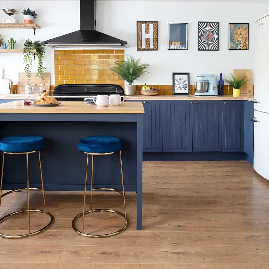 yellow metro blacksplash design in contrast with blue cabinetry and wooden flooring