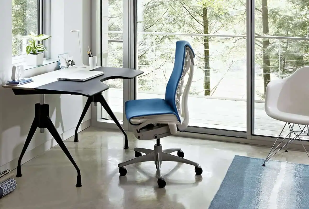 blue office or study chair in an office with a black desk, a desk plant and a glass door.