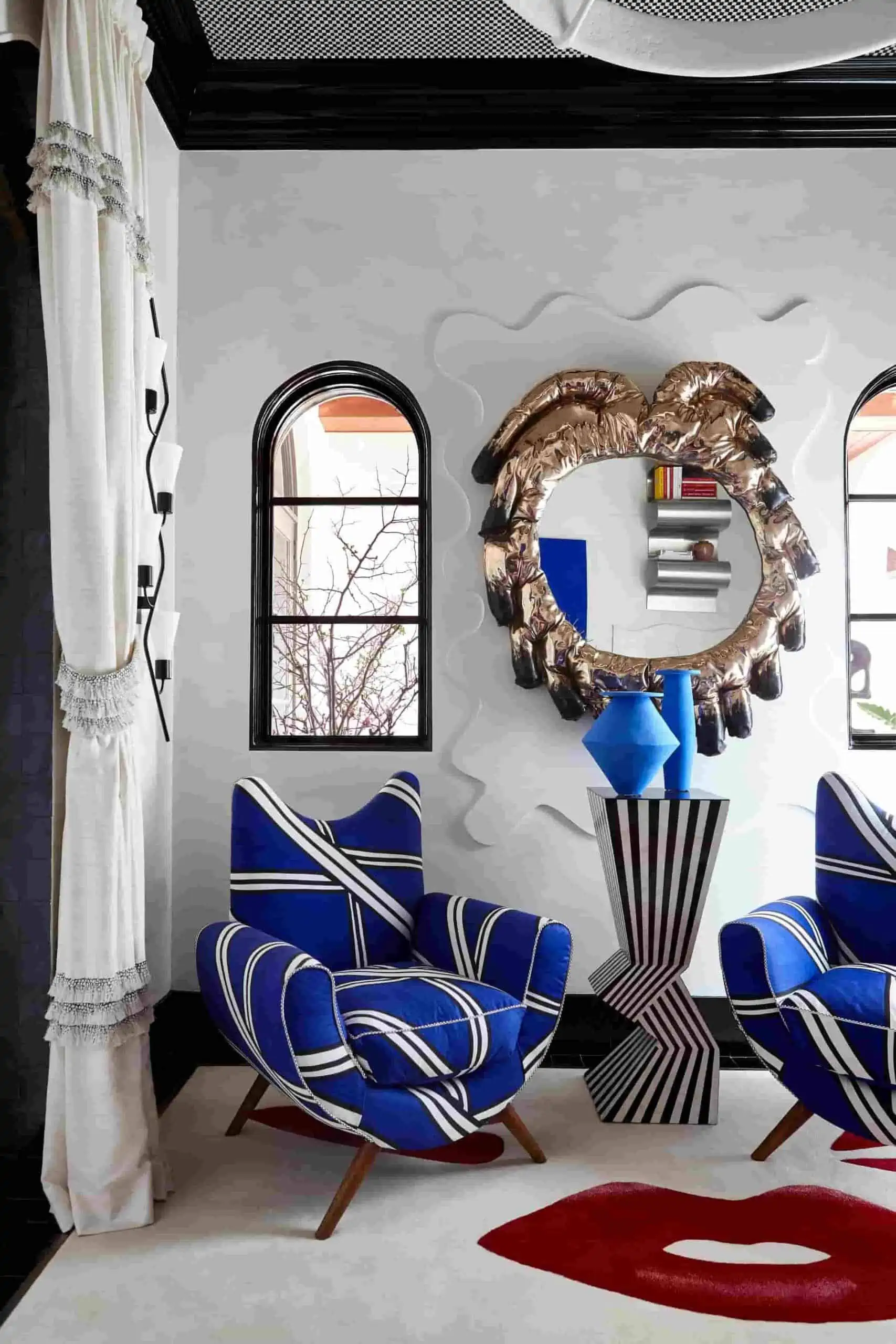 Quirky patterned armchair with striking blue color placed in a living room with wall mirror and a white rug.