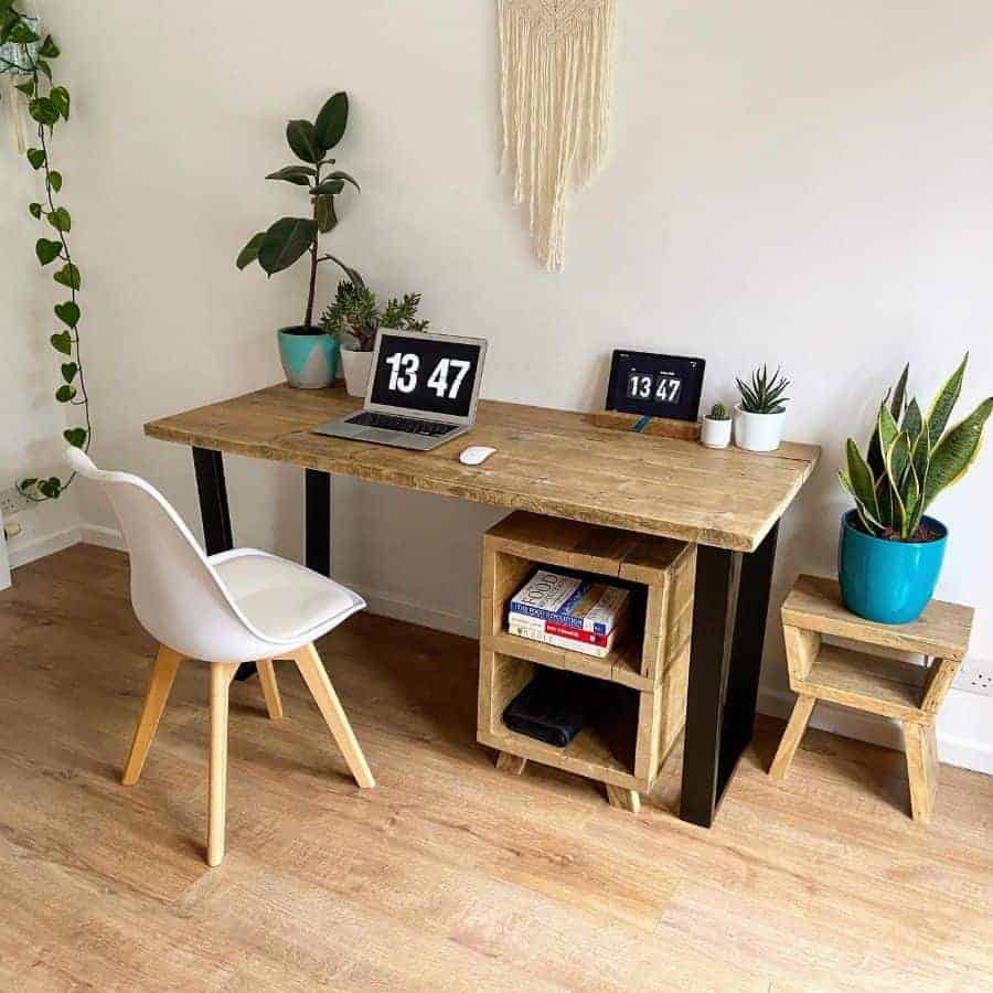 white chair with wooden frame, laptop, indoor plants, table with black body, wooden coloured top, small cabinets