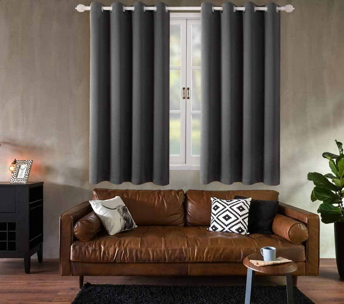 Grey sill drapes in living room with brown sofa 