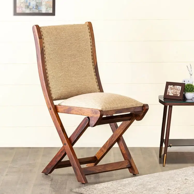 brown wooden foldable chair placed in a home setting with wooden floors, a side table and a house plant