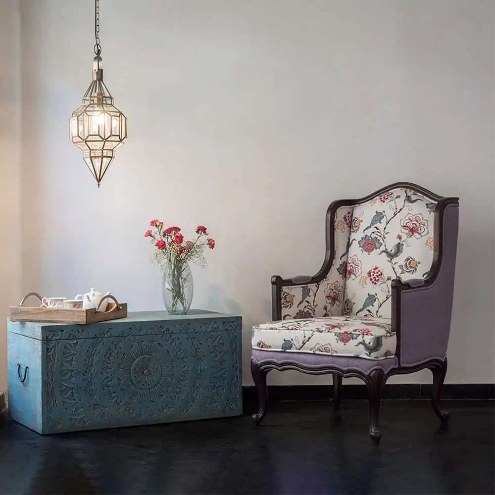 Beautiful Armchair in a living room with a n eccentric wooden box used as a table, with potted flowers and a lamp