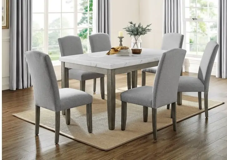 White marble top dining table with wooden frame, rectangle shape with 6 light gray cushion chairs with wooden legs,in a dining room with large windows