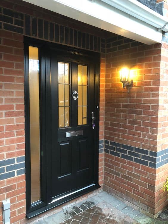 Black wood and bricks house door with outdoor lamp