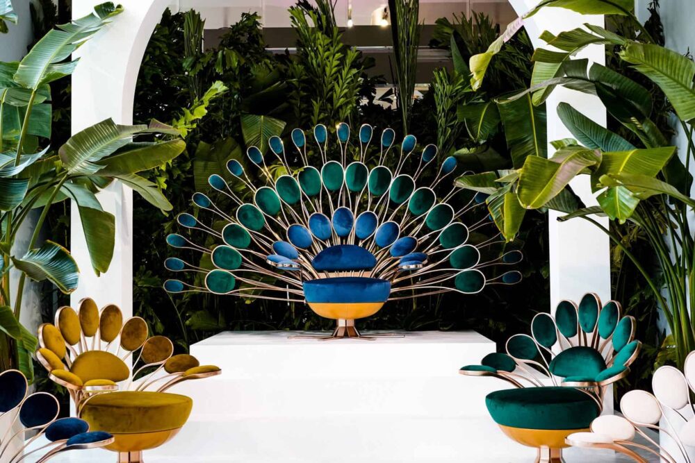 Beautiful blue peacock design sculptural furniture placed outside, surrounded by trees and plants.