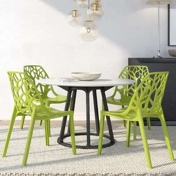 plastic dining table set with green chairs, white table top and black body, in a setting with ample outdoor lighting