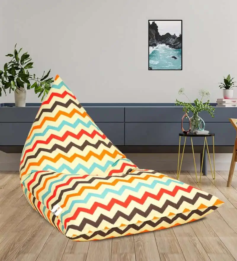 multicolored bean-bag in a home setting with wooden flooring, side table, blue cabinet and a house plant