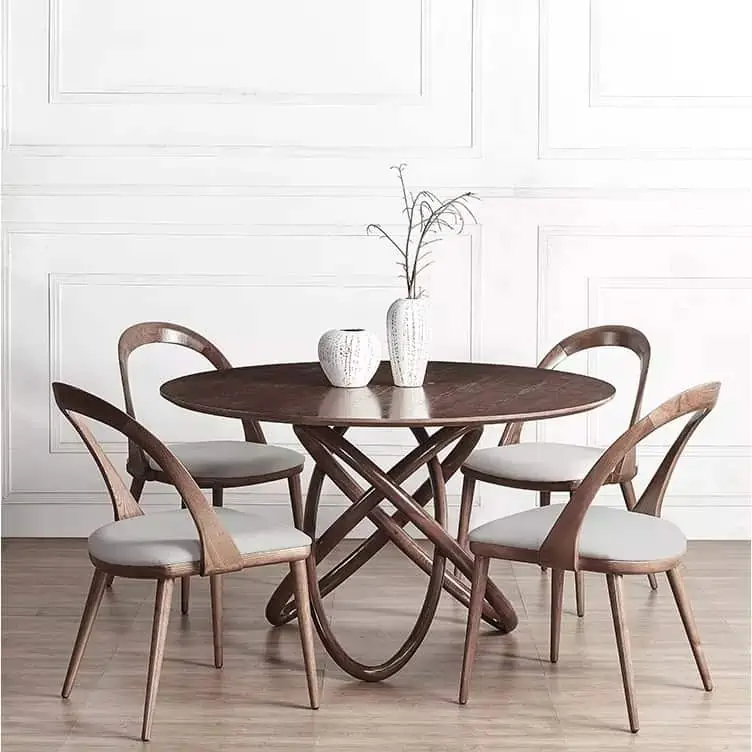 Round top dining table set in brown colour, unique design chairs with light gray cushions, in a room with white walls and light brown floor