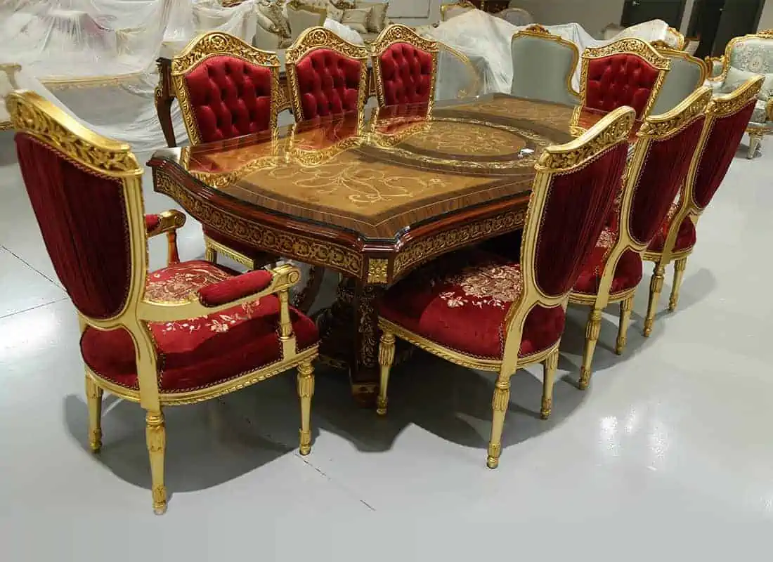 table with brown glossy decorated top, 8 chairs with red cushion and golden body, in a showroom setting