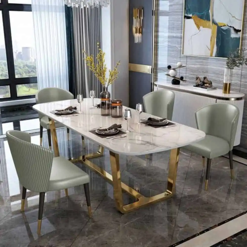 dining table set with a white top, golden coloured steel frame, light green chairs with golden steel legs, in a dining room with gray granite flooring and colourful walls