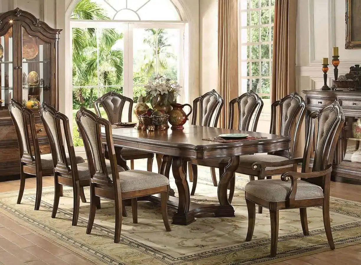 Dark brwon wooden vintage dining table with 8 chairs, light gray seats in a room with other vintage furniture