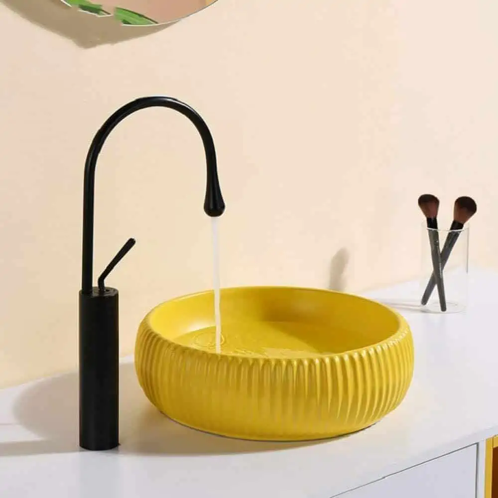 yellow washbasin with black tap in a bathroom