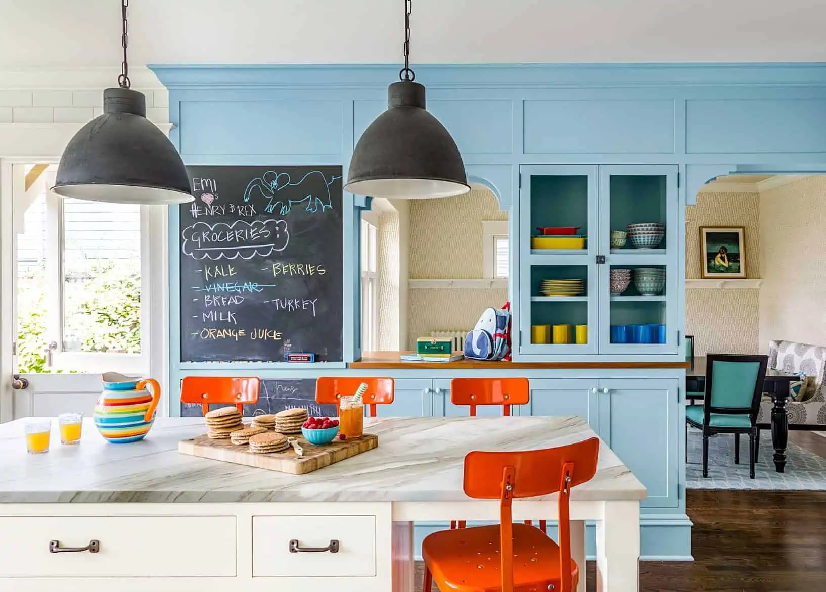 sky blue kitchen cabinets with white dinner table and orange chairs