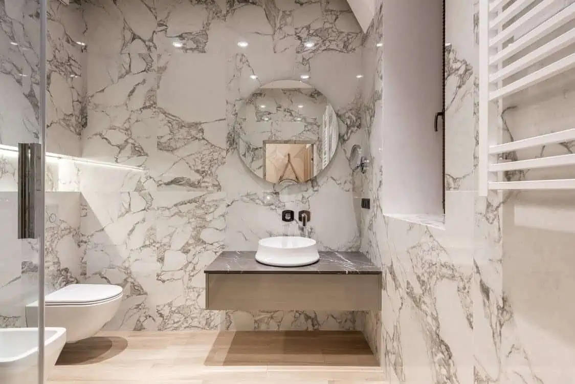 marble design walls in a bathroom with a mirror and ceramic washbasin design with cabinet and a mirror in hall