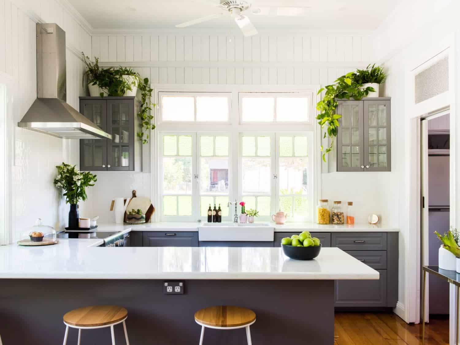 white kitchen counters with indoor plants, two chairs and a chimney