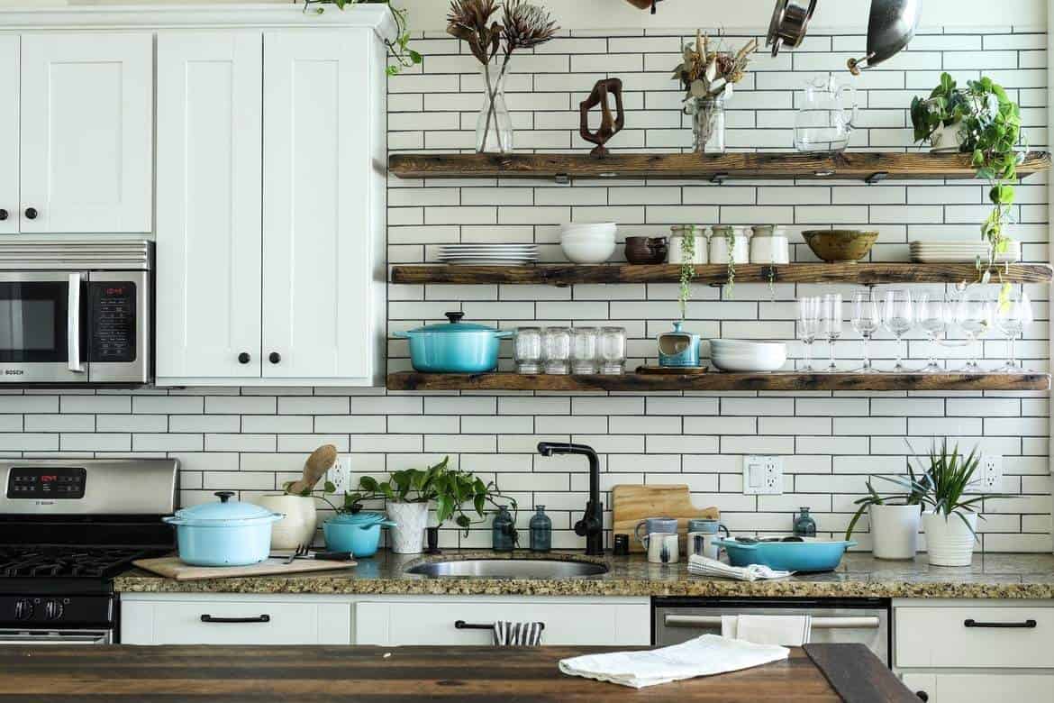 brown floating shelves with potted plants with brown counters and white cabinets