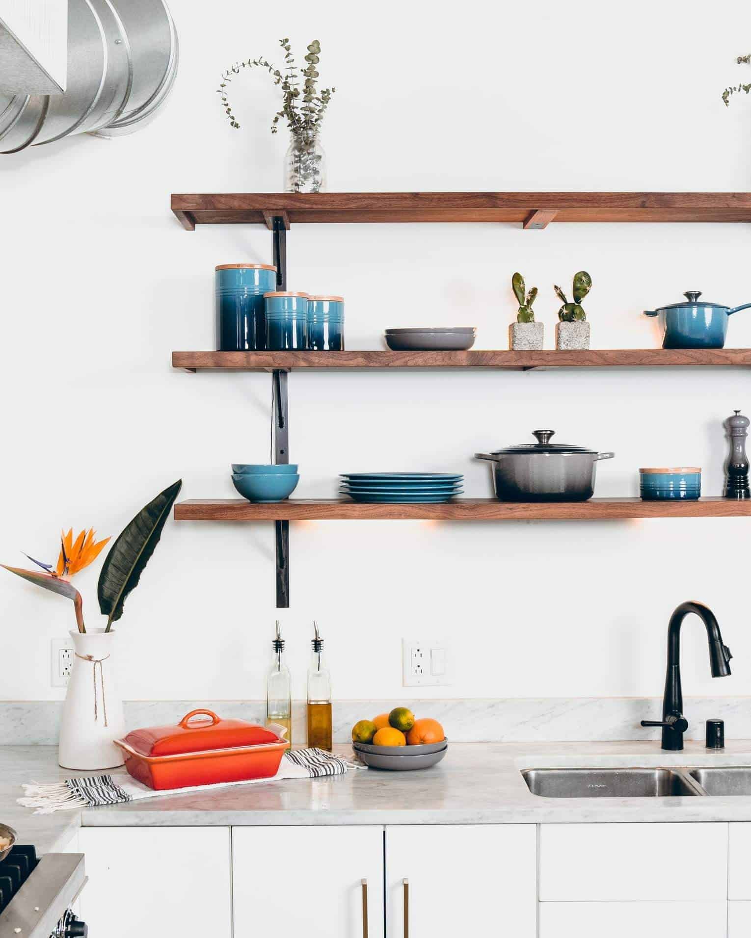 floating shelves in a kitchen with white interiors with a black tap
