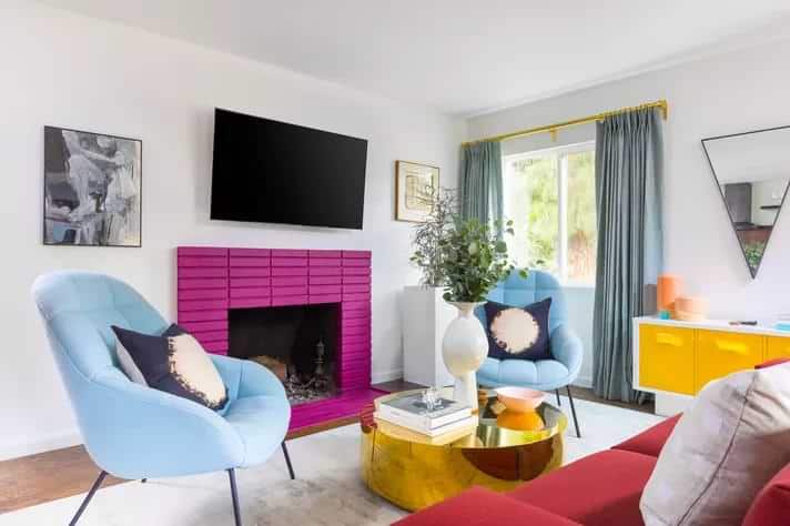 Triadic colour scheme living room with blue chairs and pink tile fireplace