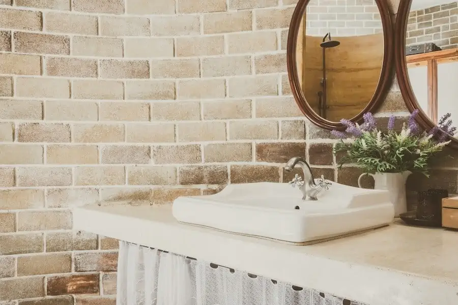 white washbasin with wooden framed mirror in a bathroom