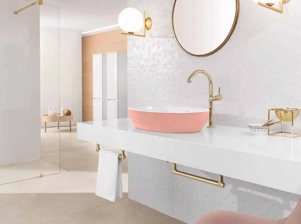 washbasin in baby pink colour with a round mirror and white counters