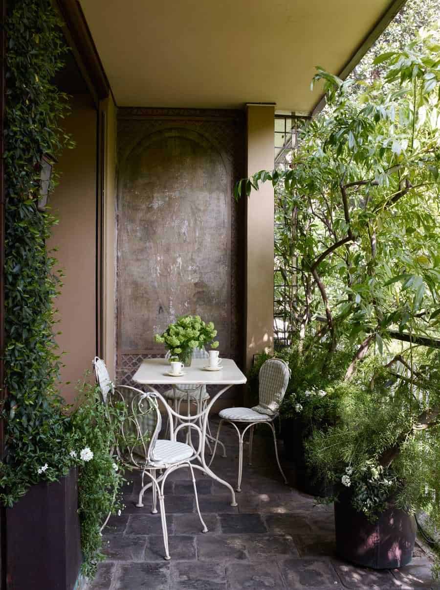 Compact old balcony with creeping plants and white seating furniture