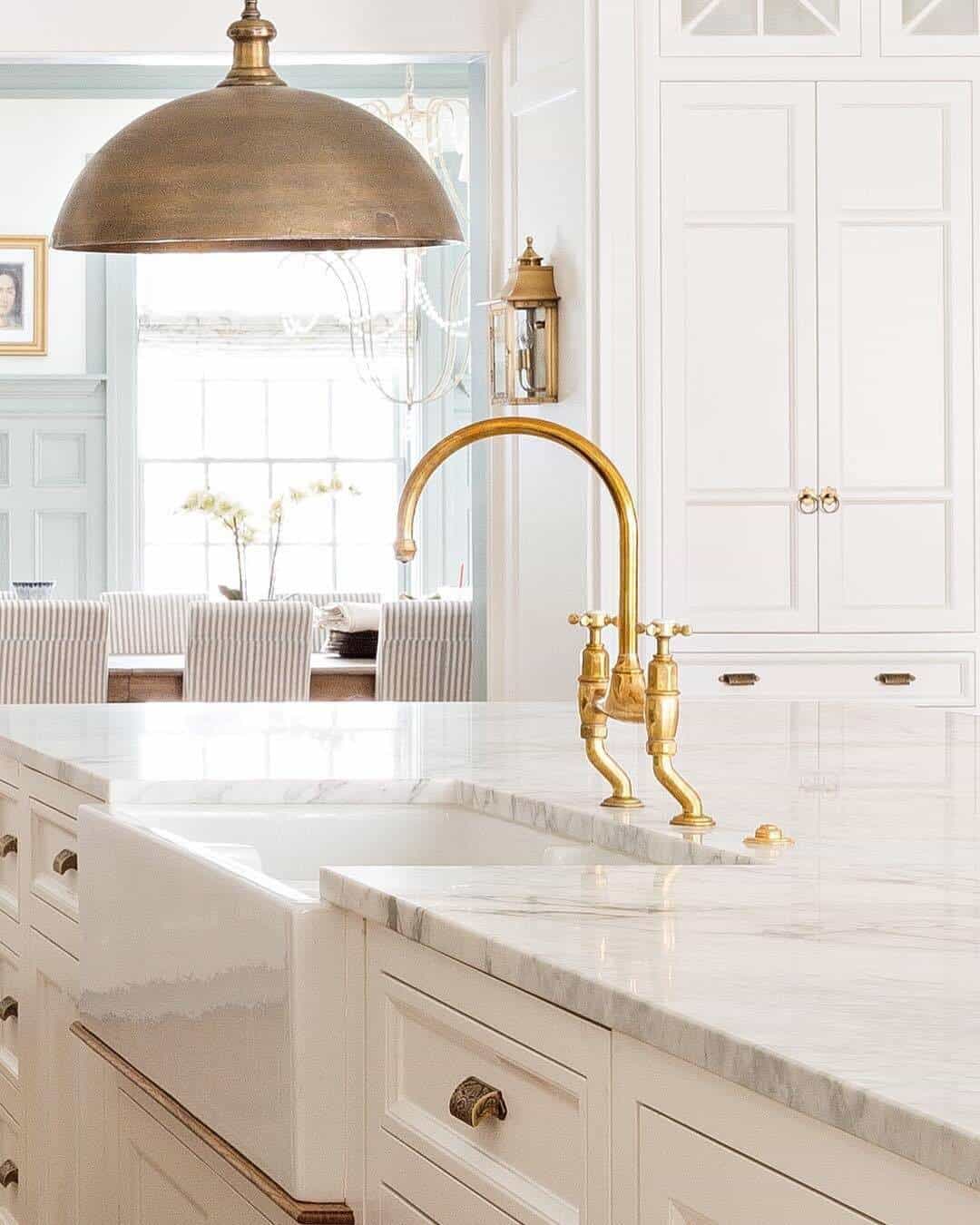 golden faucet in a kitchen with white interiors, sink, and a lamp