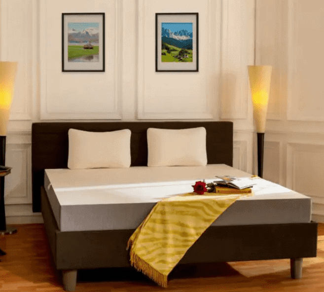 white bed, coloured pillows, side table, wall hangings