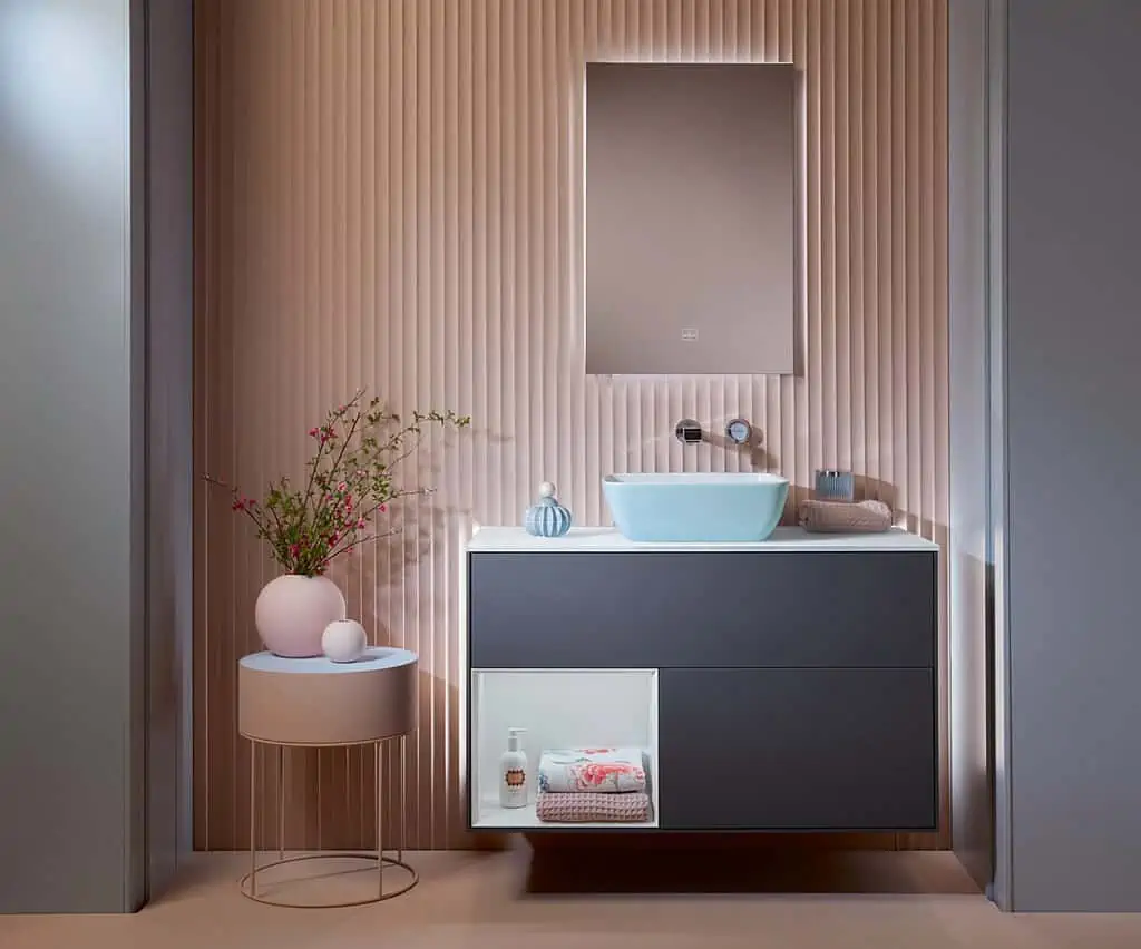 blue sink in a pink walled bathroom with a mirror and a cabinet