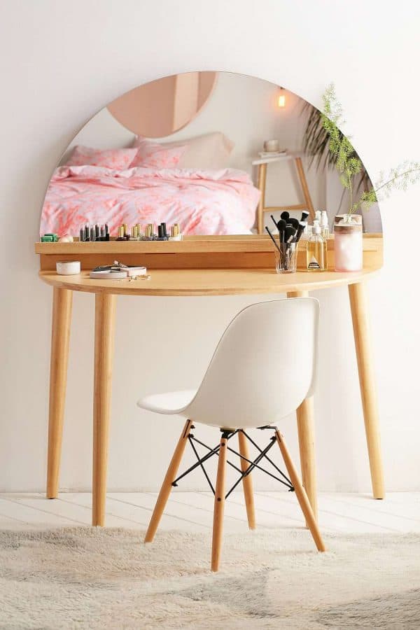 A unique wooden dressing table design with a half-moon shaped mirror, minimum storage space, and a matching chair, in a white room.