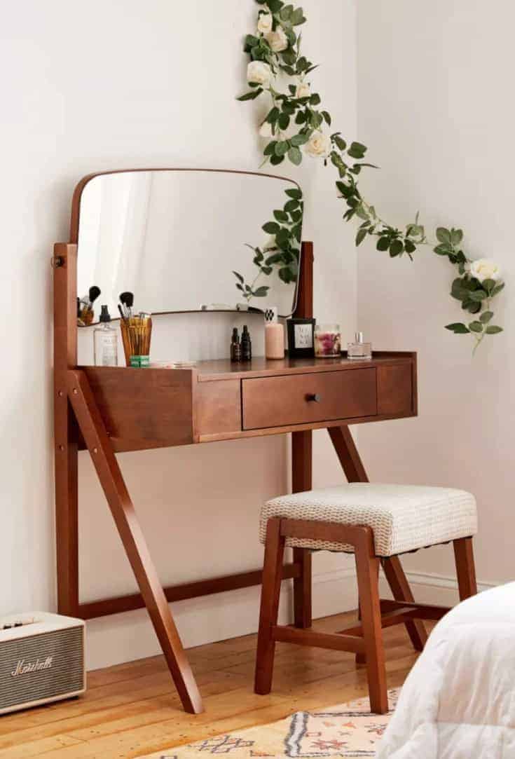 A stylish wooden dressing table design with a horizontal rectangular mirror, minimum storage space, and a matching stool, in a white room.