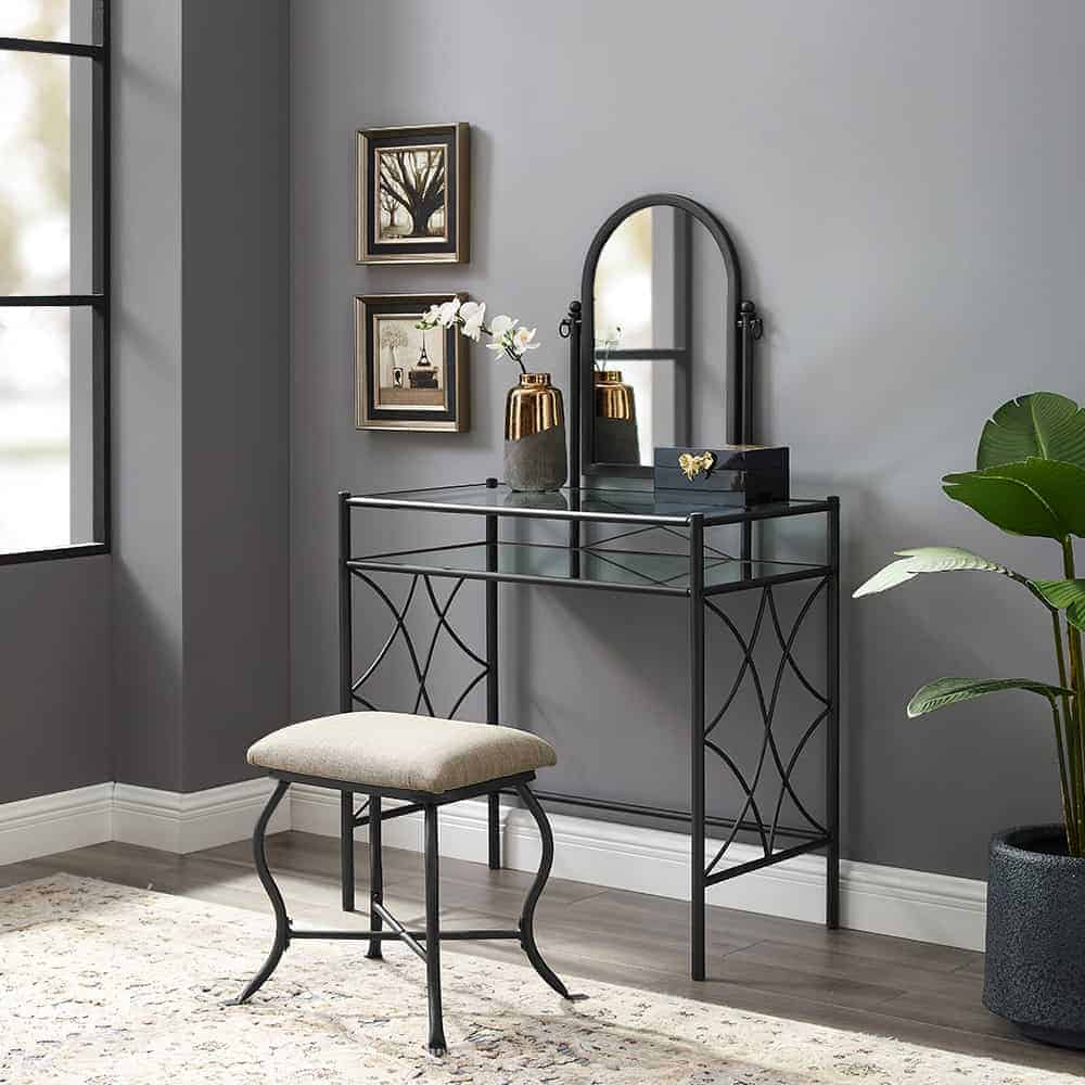 A stylish, metallic, black-colored dresser with a small mirror, minimum storage space, and a matching stool, in a gray room.