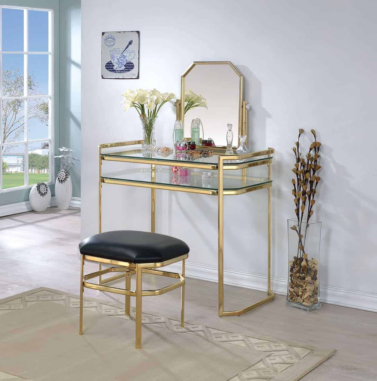 An elegant honey colored metallic dressing table design with a small square mirror, minimum storage space, and a matching stool, in a white room.