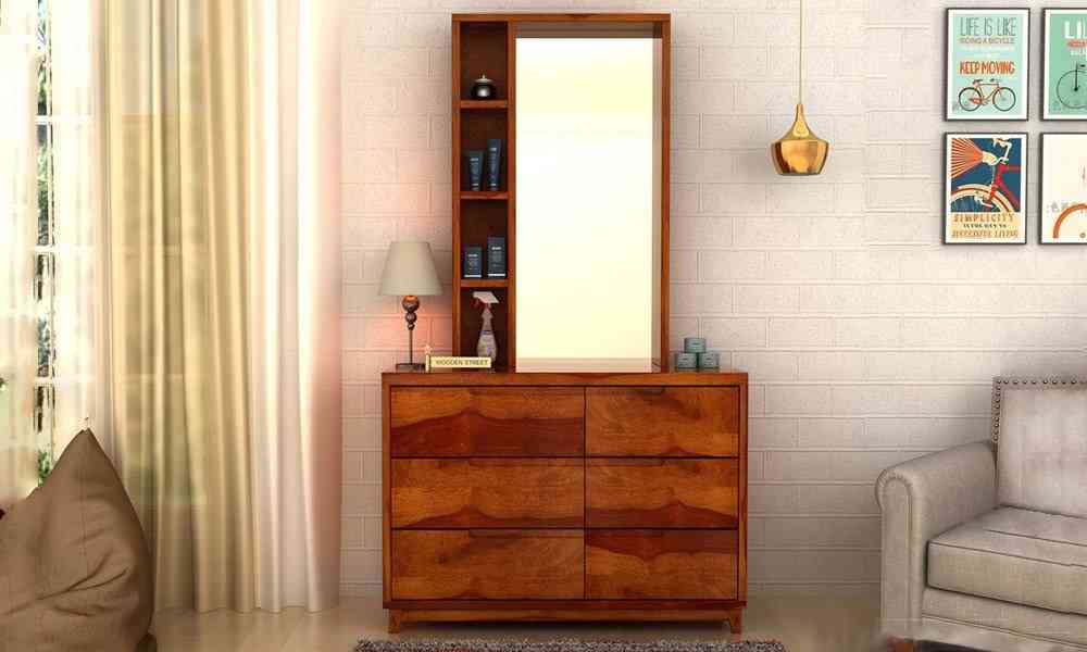 A classy wooden dresser with a rectangular mirror and good storage space, in a white room.