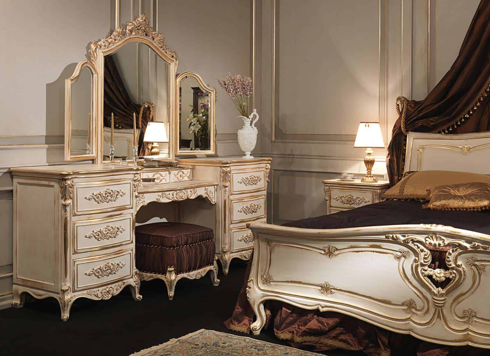 A white-colored royal dressing table design with huge 3-fold mirrors, lots of storage space, and a matching stool, in a white bedroom.