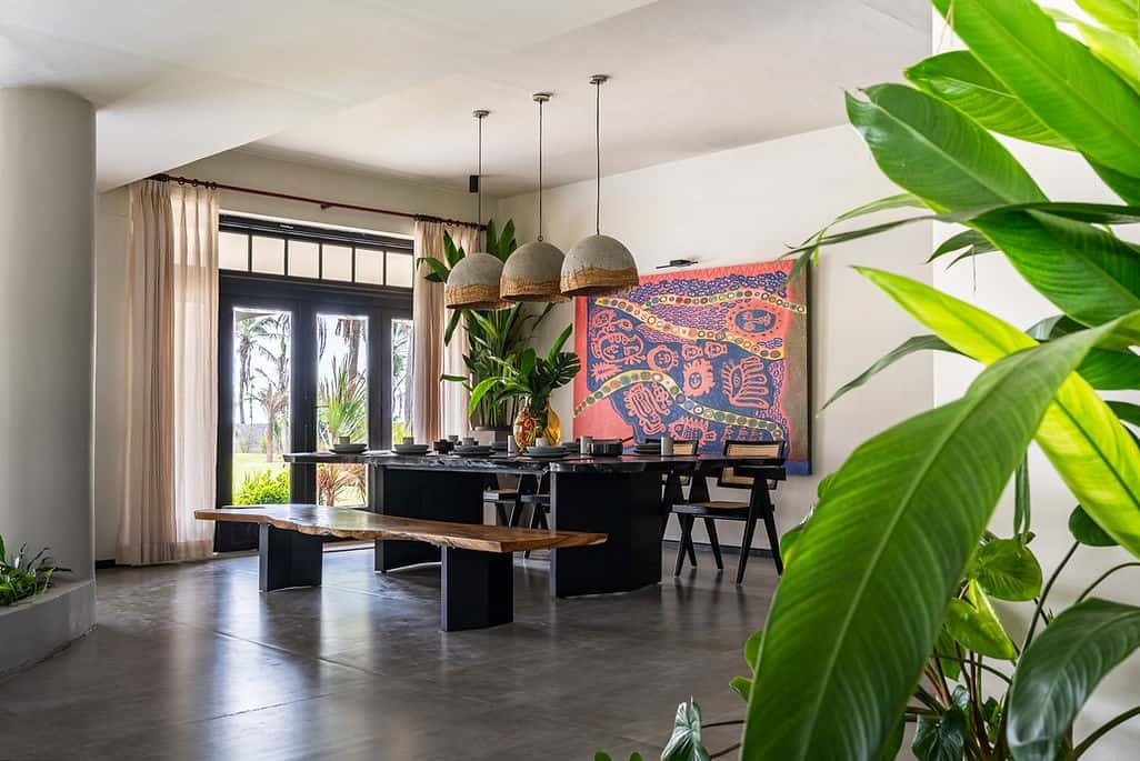 living room with multicolor painting, black table, ceiling lamps and plants