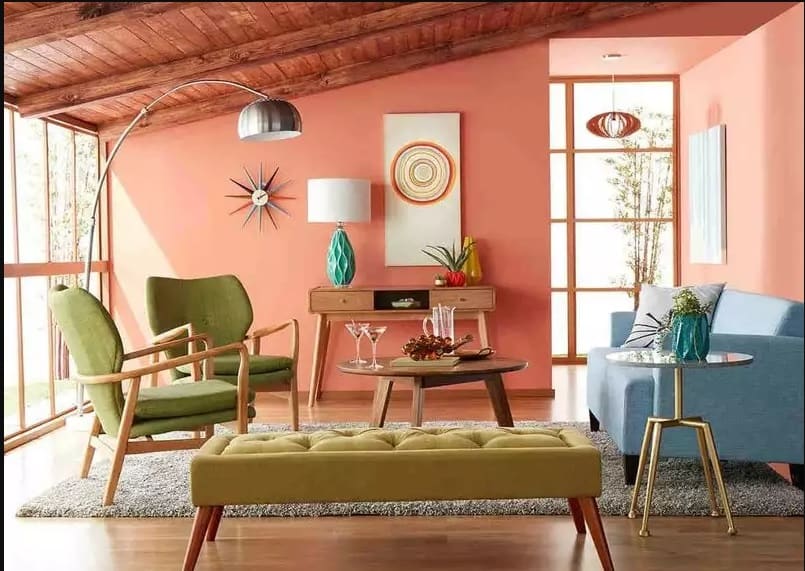 Peach walls, blue sofa and green armchair with wood flooring for this living room